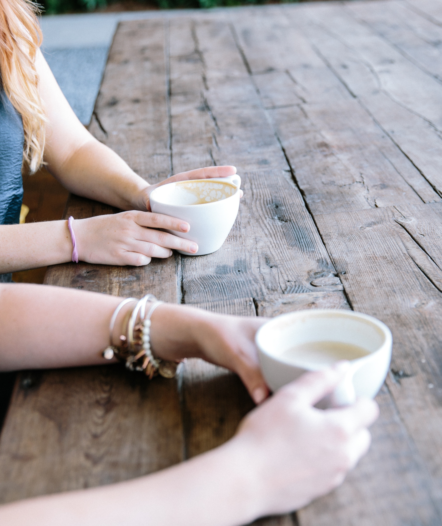 Wooden table with two people with coffee mugs