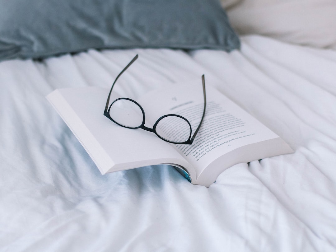 A book and glasses on the bed